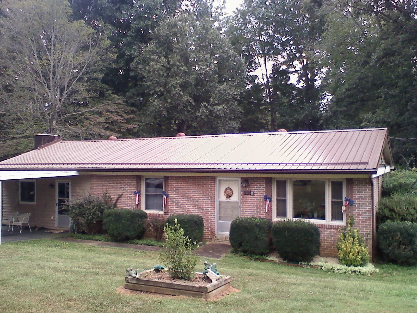 Bronze metal roof on a brick ranch home with a carport in Croton On Hudson