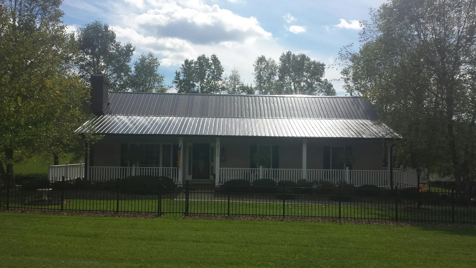 Gray metal roof on a brick ranch with a full width front porch — Gutter Guard Installation work by our crew in Croton On Hudson