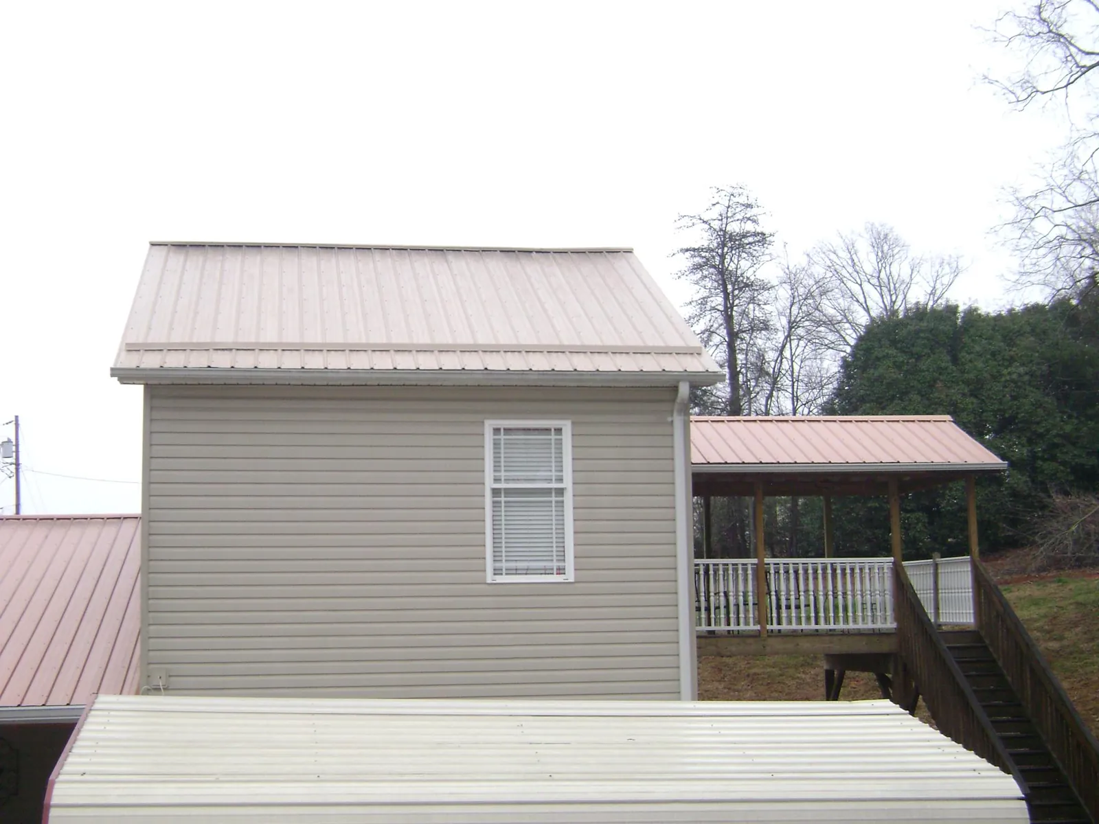 Tan metal roofs on a two story addition and attached porch, from a Roof Replacement job in Croton On Hudson