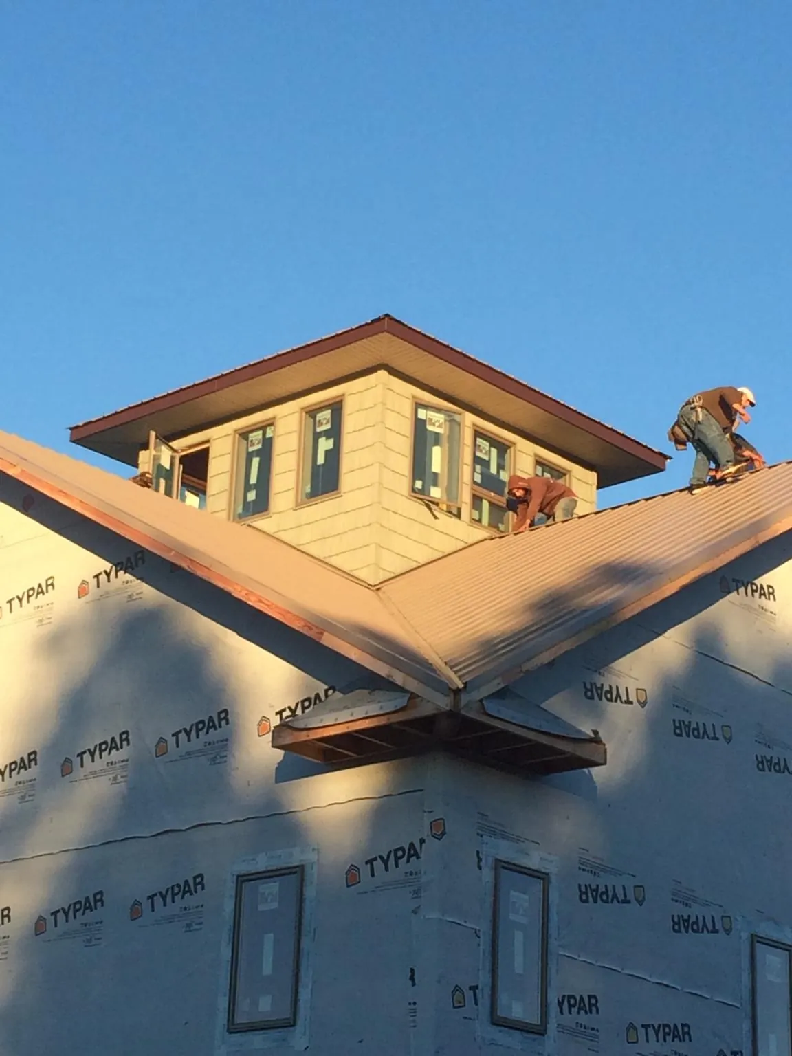 Roofers working around a rooftop cupola on a new metal roof at sunset — Roof Waterproofing in Croton On Hudson by Roofing Brothers